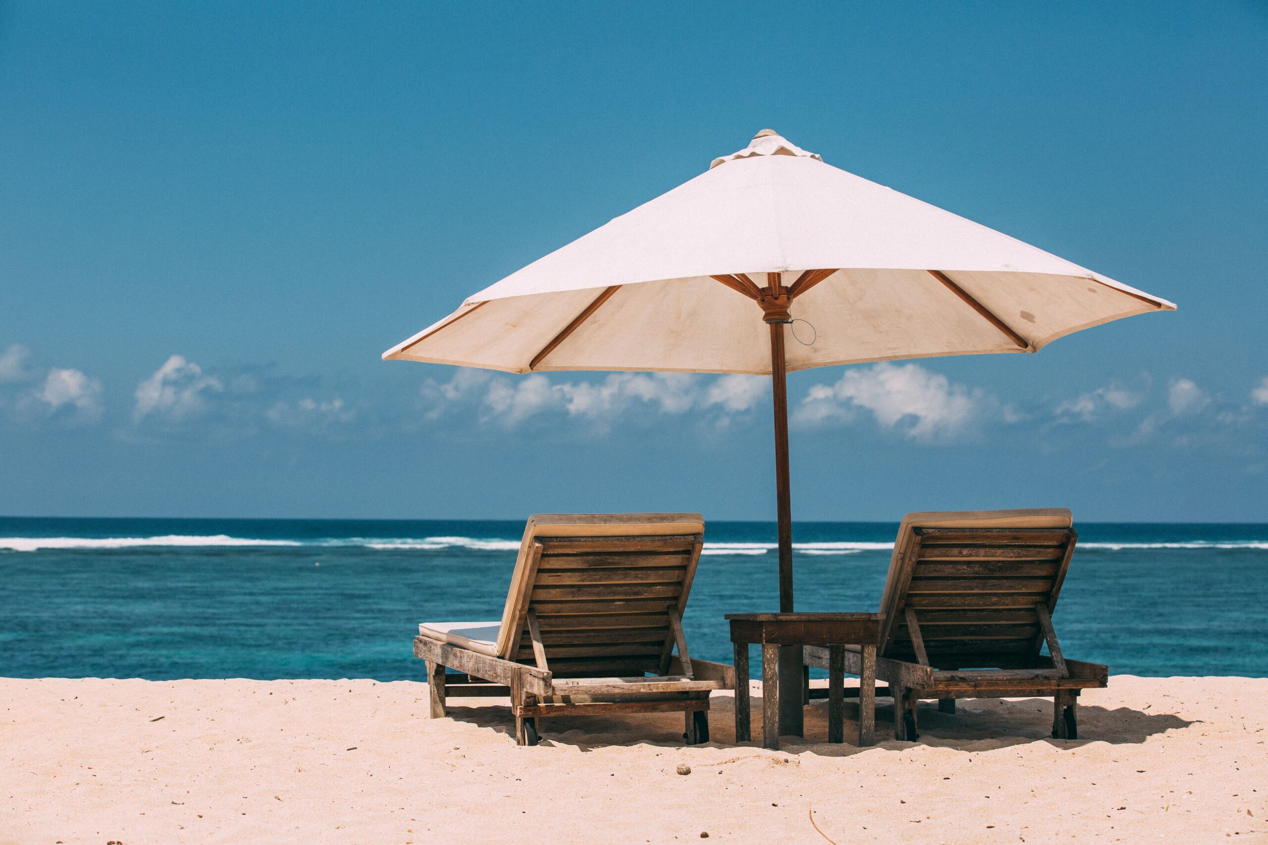 Dwa leżaki pod parasolem na piaszczystej plaży nad morzem
