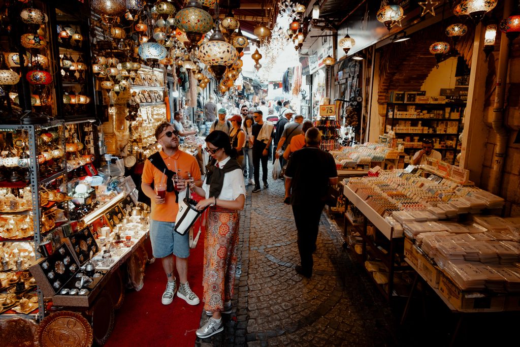 Turyści oglądający pamiątki i kolorowe lampy na zagranicznym bazarze podczas wakacji.